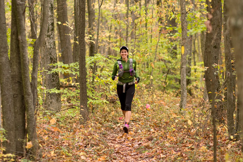 A woman running through the woods in the fall.