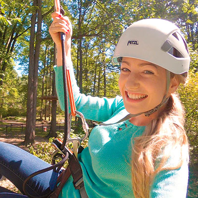 A woman wearing a helmet on a zip line.